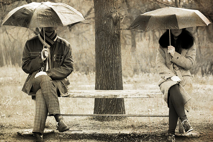 Two-sitting-at-bench-in-rainy-day