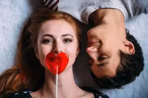 Loving-couple-lying-on-the-floor-girl-covers-her-mouth-with-a-lollipop