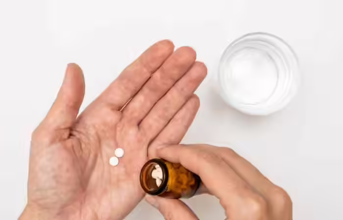A person taking blood-thinning pills from a bottle