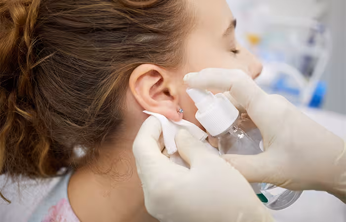 A piercer cleaning a piercing hole
