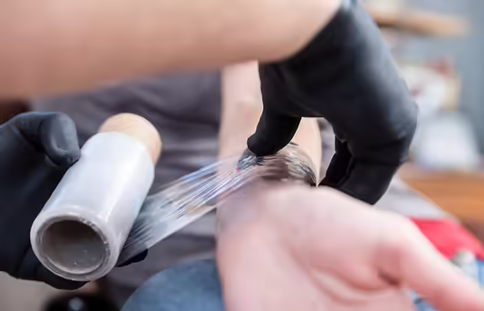 Tattoo artist wrapping the tattoo
