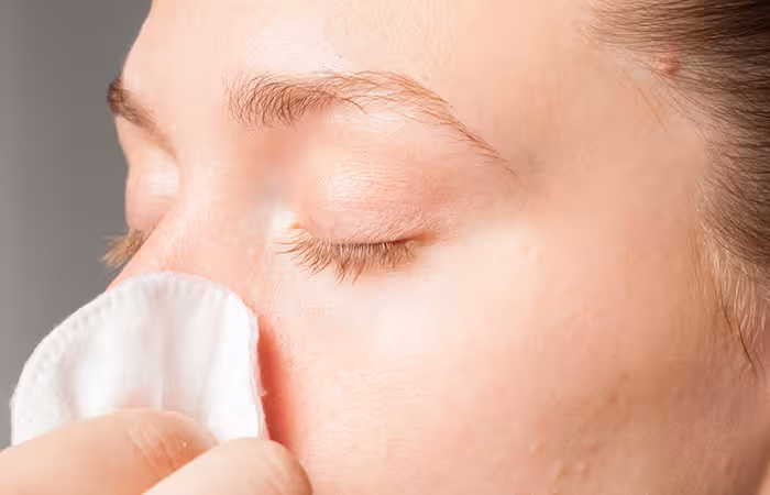 A woman cleaning a nose piercing with cotton