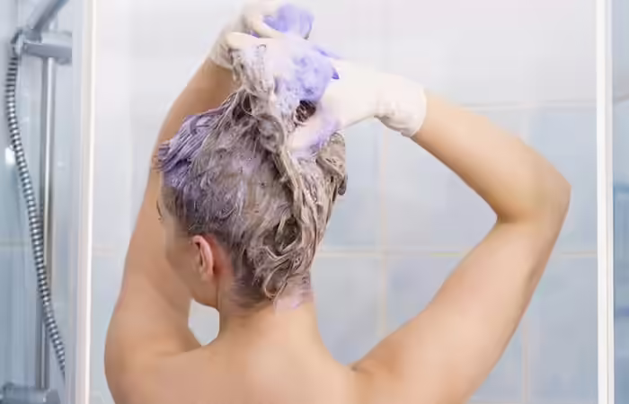 Woman using purple shampoo to maintain oil slick hair