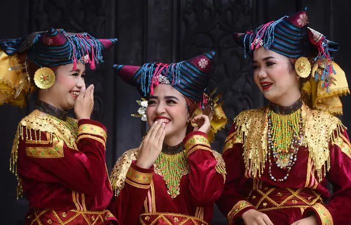 3 Minangkabau tribal girls are smiling at each other.