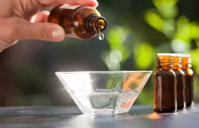 Closeup of hand mixing essential oils to prepare castile soap shampoo