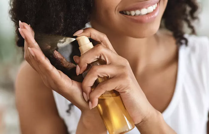 Woman using hair care product to repair heat-damaged curly hair