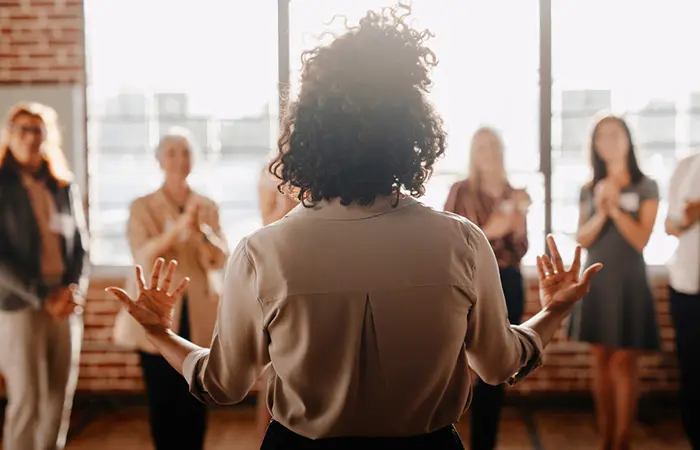 Backshot of a female boss while she gives a motivating speech to her fellow colleagues.