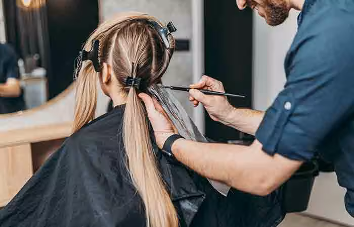 A hairspecialist is bleaching the hair of a woman.