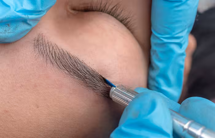 An aesthetician microblading a woman’s eyebrow