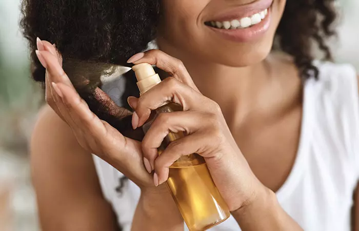 Woman using a conditioning spray on her afro hair