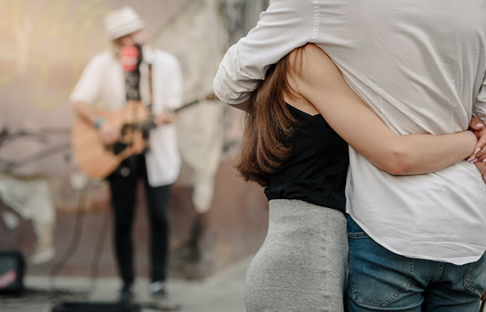 Couple hugging while listening to a street artist