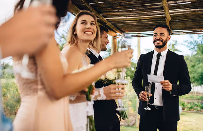 Best man giving speech before raising a toast at wedding reception.