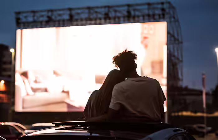 A romantic couple on an outdoor date watching a drive-in movie A romantic couple on an outdoor date watching a drive-in movie
