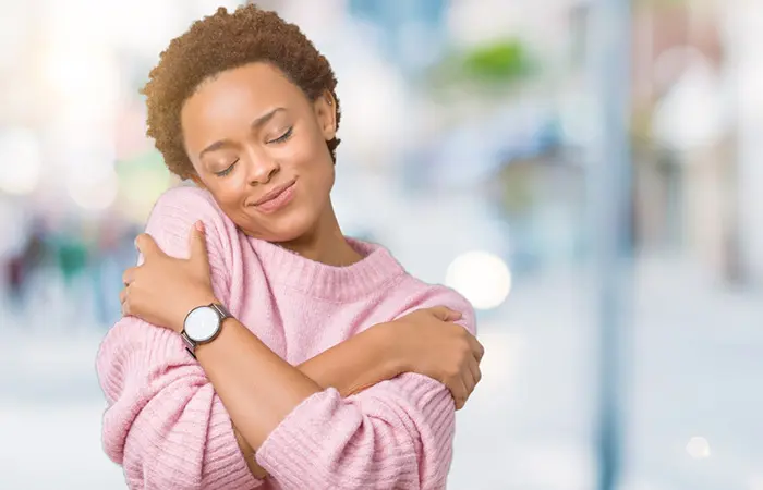 A woman showing self-love by hugging herself.