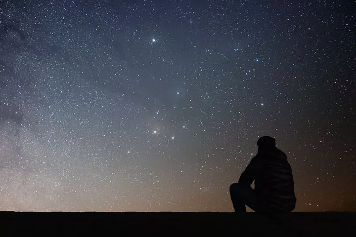 A mother is pointing at the night sky to show her child the stars.