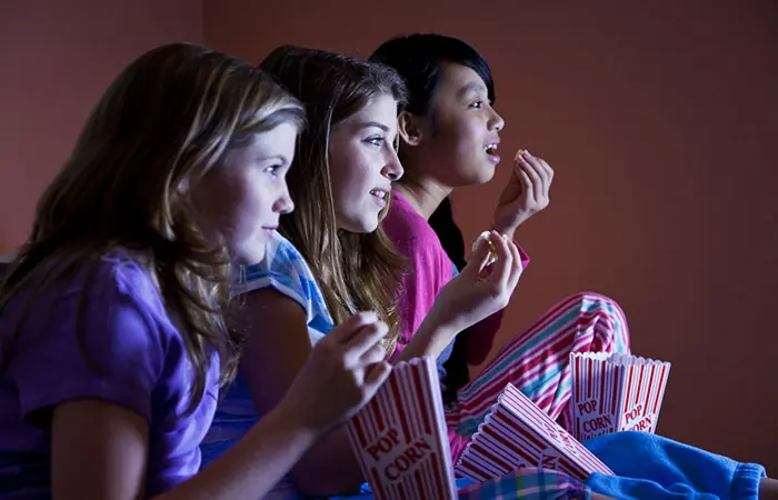 Three teens watching a movie at a teen slumber birthday party