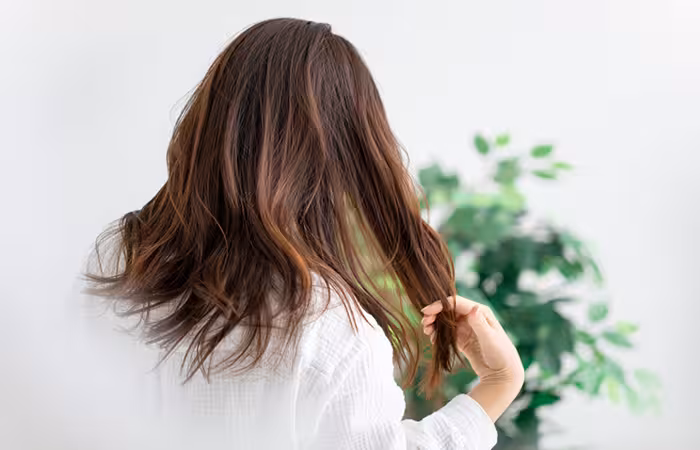 Woman running her hand through her unwashed hair